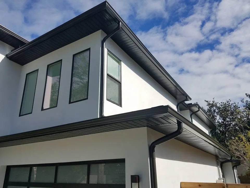 Black round downspouts dark soffit white stucco upward view, Sanford